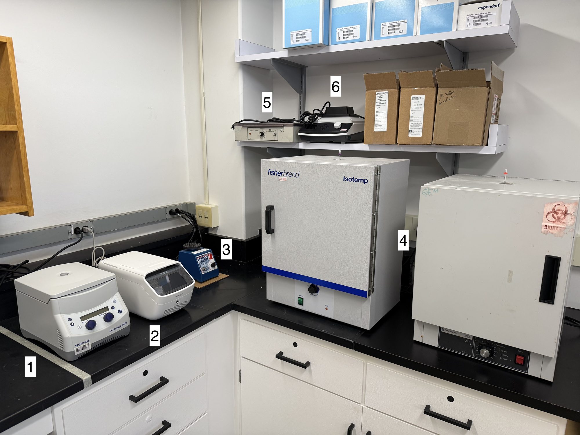 Lab bench with a centrifuge, thermocycler, vortexer, drying ovens, and other benchtop equipment