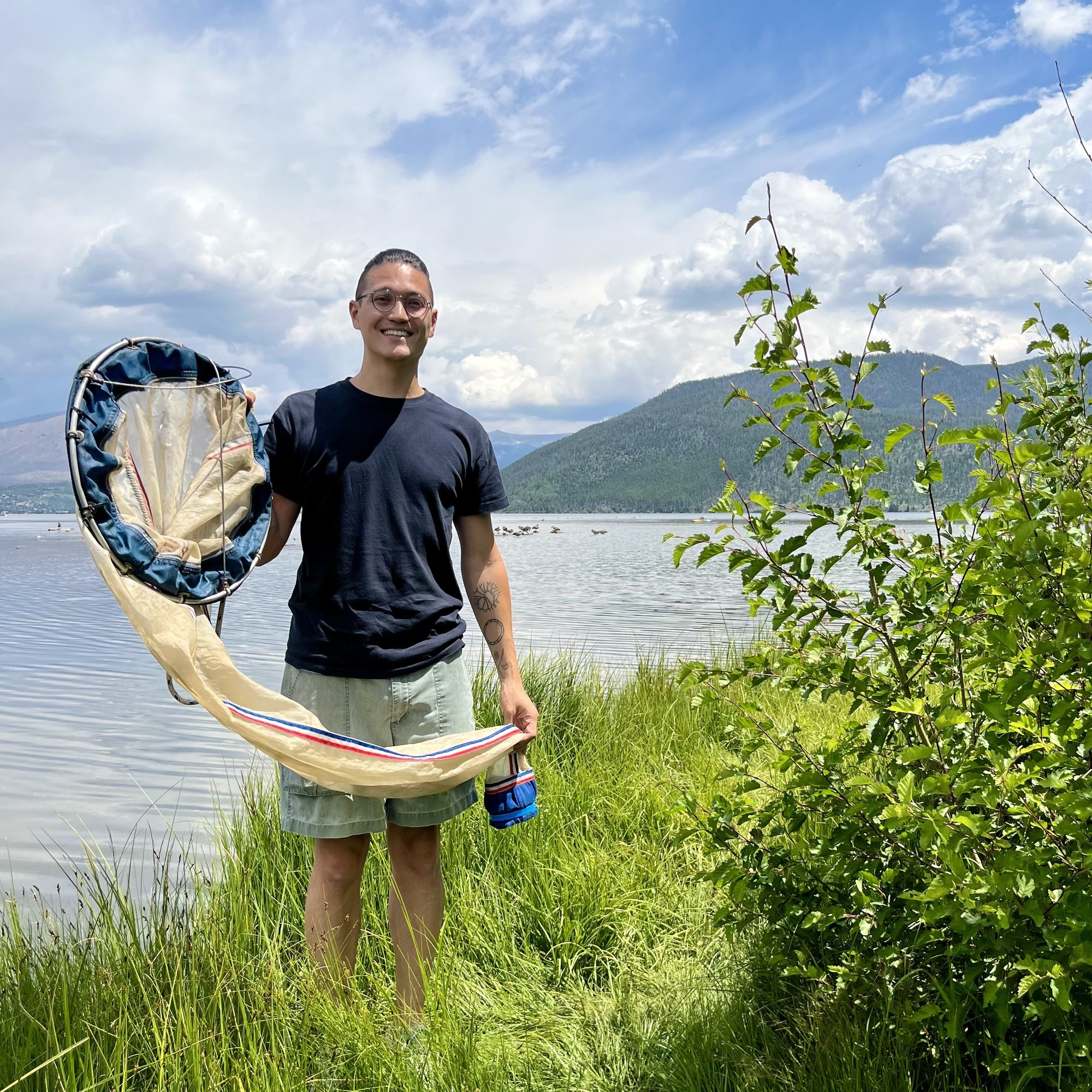 Matt Sasaki holding a plankton net beside a lake